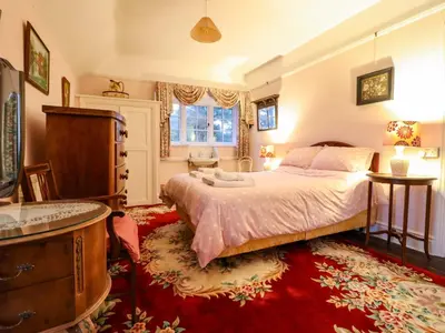 a bedroom with a large bed and a red rug at Murmur Y Don in Harlech