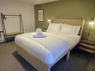 a bedroom with a large bed with a white blanket at Stylish and spacious lower ground floor apartment -Pass the Keys in Shrewsbury