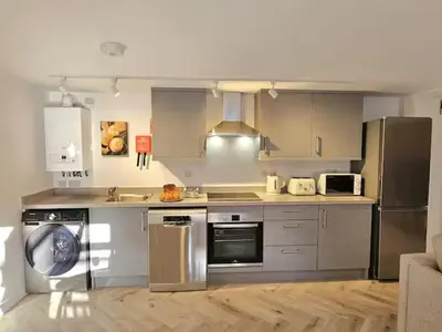 a kitchen with stainless steel appliances and wooden floors at Stylish and spacious lower ground floor apartment -Pass the Keys in Shrewsbury
