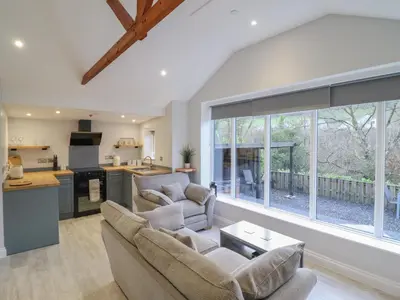a living room with two couches and a kitchen at Lodge at Nadur in Machynlleth