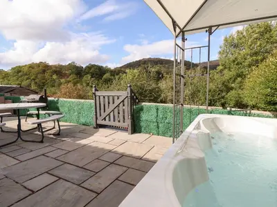 a hot tub on a patio with a table and a picnic table at Castellolwg in Llangollen