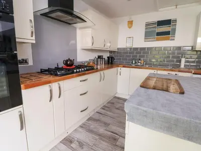 a kitchen with white cabinets and a stove top oven at Castellolwg in Llangollen