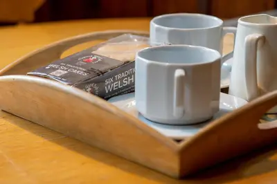 a tray with two cups and a book on a table at The Granary - Wild Swimming, Sauna, Peace & Quiet, Nr Bala in Corwen