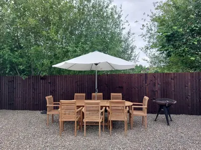 a wooden table with chairs and an umbrella at 1 Clarkes Lane in Oswestry