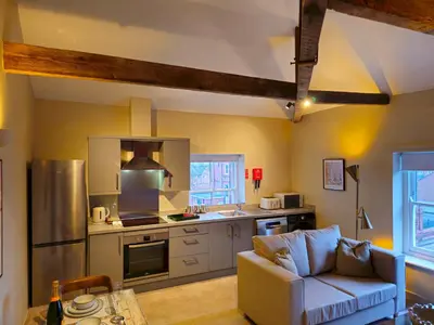 a living room with a couch and a kitchen at Stylish and newly renovated penthouse apartment - Pass the Keys in Shrewsbury