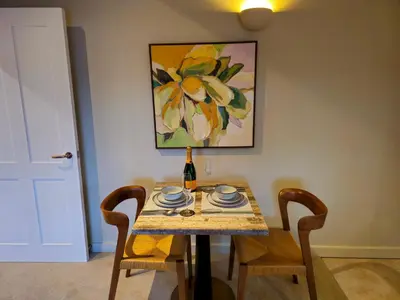 a table with a bottle of wine and two chairs at Stylish and newly renovated penthouse apartment - Pass the Keys in Shrewsbury