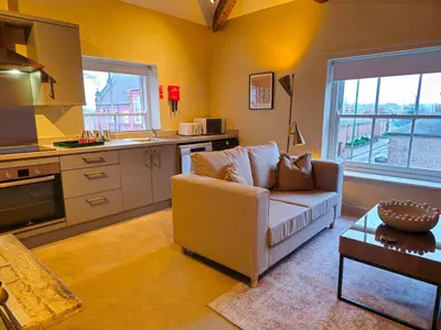a living room with a couch and a kitchen at Stylish and newly renovated penthouse apartment - Pass the Keys in Shrewsbury