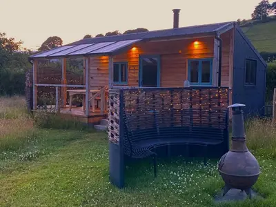 a log cabin with a large deck and a house at 1 Bed in Llanfihangel-y-Creuddyn oc-c34624 in Llanfihangel-y-creuddyn