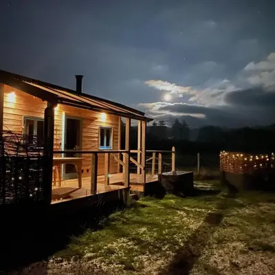 a log cabin with lights on the porch at night at 1 Bed in Llanfihangel-y-Creuddyn oc-c34624 in Llanfihangel-y-creuddyn