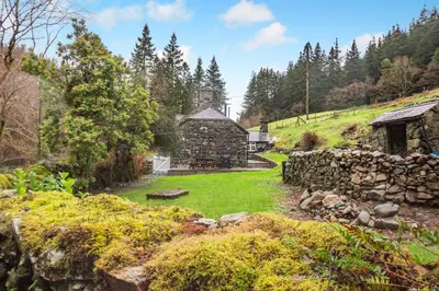 an old stone house with a stone wall and a yard at 4 Bed in Ganllwyd oc-g34601 in Mallwyd