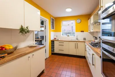 a kitchen with yellow walls and white cabinets at Spacious 4 bed home to sleep 9, parking for 4 cars in Shrewsbury