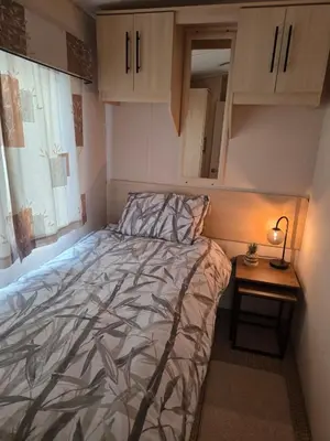 a small bedroom with a bed and a night stand at Premium 3 Bedroom Static Caravan with Sea Views Aber Bay in Aberystwyth