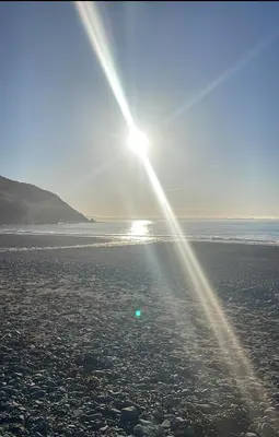 a beach with the sun shining on the sand at Premium 3 Bedroom Static Caravan with Sea Views Aber Bay in Aberystwyth