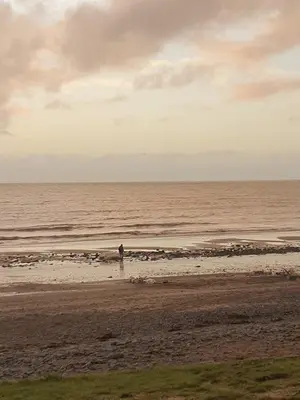 a person standing on a beach near the ocean at Premium 3 Bedroom Static Caravan with Sea Views Aber Bay in Aberystwyth