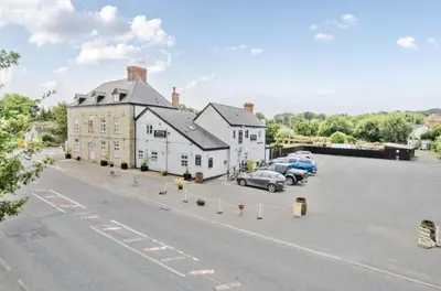 a large white building with cars parked in a parking lot at Mortimers Cross Guest House in Mortimer's Cross