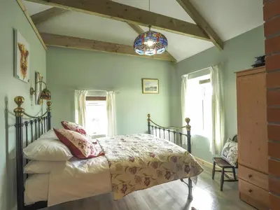 a bedroom with a bed with pink and white sheets at Sgubor Delyn Aberystwyth in Llanrhystyd