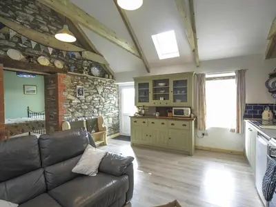 a living room with a couch and a stone wall at Sgubor Delyn Aberystwyth in Llanrhystyd