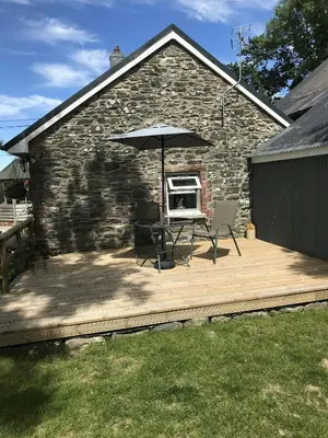 a patio with an umbrella and a table and chairs at Sgubor Delyn Aberystwyth in Llanrhystyd