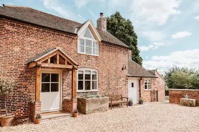 a brick house with a white door and a bench at Little Whitley - Luxury Country Cottage in Shrewsbury