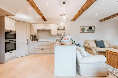a kitchen with white cabinets and a living room at Little Whitley - Luxury Country Cottage in Shrewsbury