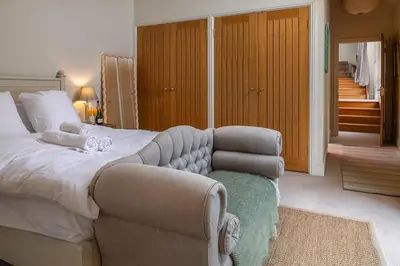 a bedroom with a large bed and a chair at Blackhill barn - in the heart of the Cotswolds in Craswall