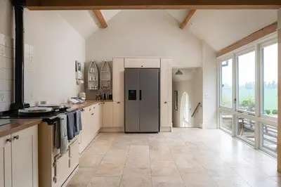 a kitchen with a refrigerator and a large window at Blackhill barn - in the heart of the Cotswolds in Craswall