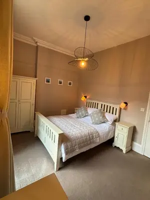 a bedroom with a white bed and a chandelier at Swn Y Mor 3 Aberystwyth in Aberystwyth