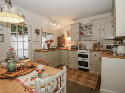 a kitchen with white cabinets and a wooden table at 8 Welsh Street in Bishops Castle