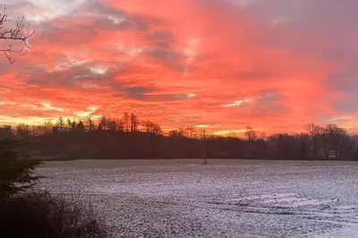 a sunset over a snowy field with a red sky at Lavender Lodge