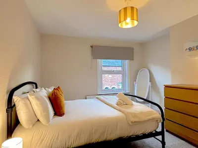 a bedroom with a bed with a dresser and a window at 2 bedroom house 12mins walk to town in Shrewsbury