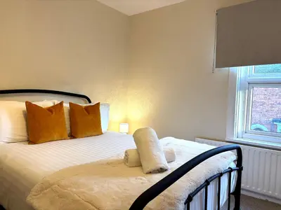 a bedroom with a bed with orange pillows and a window at 2 bedroom house 12mins walk to town in Shrewsbury