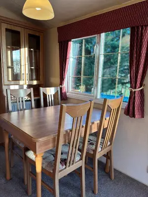 a dining room table with chairs and a large window at The Woodlands Caravan in Bryn-glâs Station