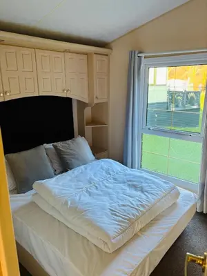 a large bed in a room with a window at The Woodlands Caravan in Bryn-glâs Station
