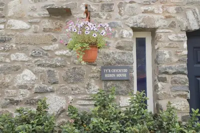 a flower pot on the side of a stone building at Abbey Cottages- Heron House in Talley