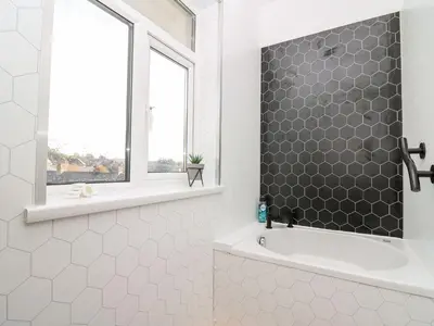 a bathroom with a shower and a tub and a window at Ty Melyn in Aberystwyth