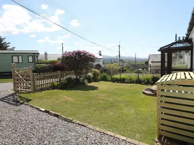 a backyard with a wooden fence and a yard at Goetra in Harlech