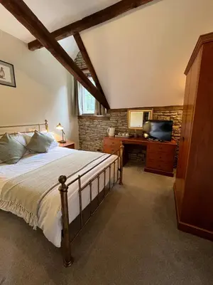 a bedroom with a bed and a desk with a television at The Coach House Inn in Shobdon