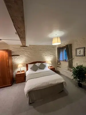 a bedroom with a large bed with two night stands and two lamps at The Coach House Inn in Shobdon