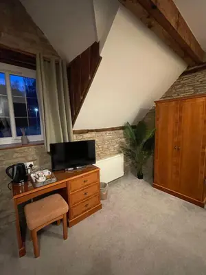 an attic room with a desk with a television on it at The Coach House Inn in Shobdon