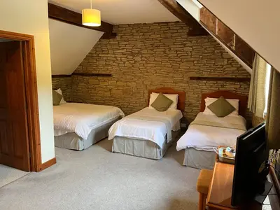 two beds in a room with a brick wall at The Coach House Inn in Shobdon