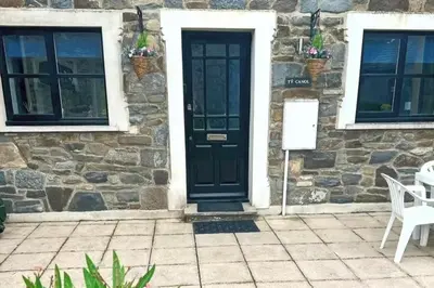 a stone house with a black door and two windows at 3 Bed Harbour-view Cottage Sleeps 6 - Dog Friendly in New Quay