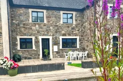 a stone cottage with a table and chairs in front of it at 3 Bed Harbour-view Cottage Sleeps 6 - Dog Friendly in New Quay