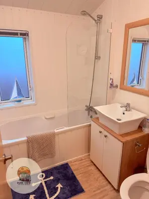 a bathroom with a sink and a tub and a toilet at Dune View Chalet in Ynys-lâs Station