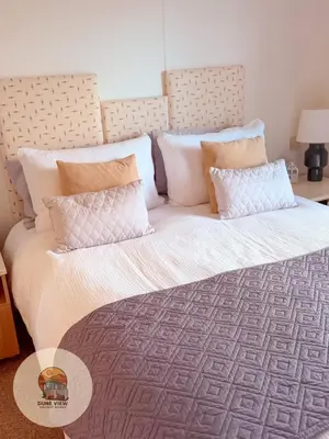 a large bed with white sheets and pillows at Dune View Chalet in Ynys-lâs Station