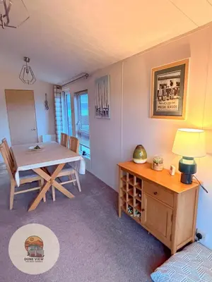 a dining room with a table and a table and chairs at Dune View Chalet in Ynys-lâs Station