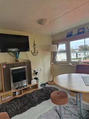 a living room with a table and a tv at Brynowen Holiday Park Borth in Borth