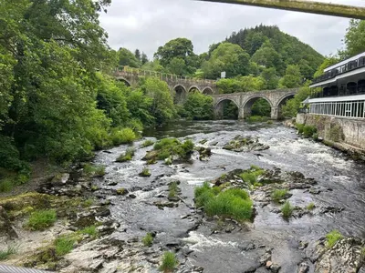 a river with a bridge in the background at Henllys Cottage in Corwen