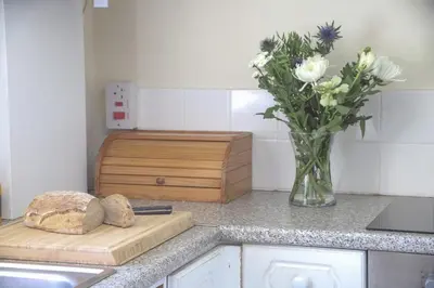 a kitchen counter with a vase of flowers and a cutting board at Abbey Cottages - Buzzards Watch in Talley