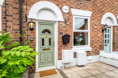 a brick house with a green door and a window at Quaint home with log burner in peaceful cul-de-sac in Shrewsbury