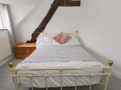 a white bed with a pink pillow on top of it at The Old Shop in Builth Wells
